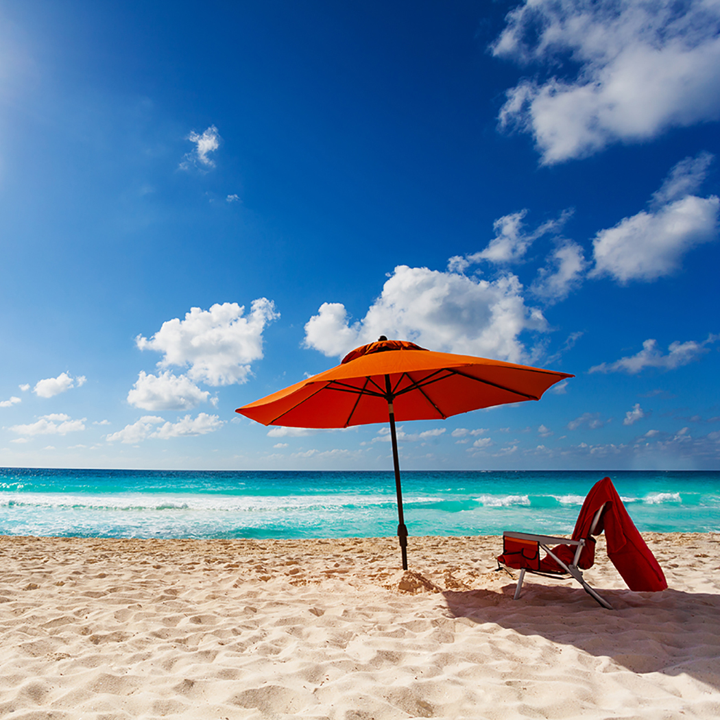 orange beach umbrella and chair at ocean edge